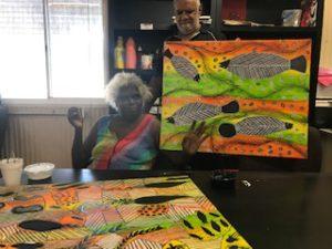 Aged Care Resident holding up Indigenous Artwork