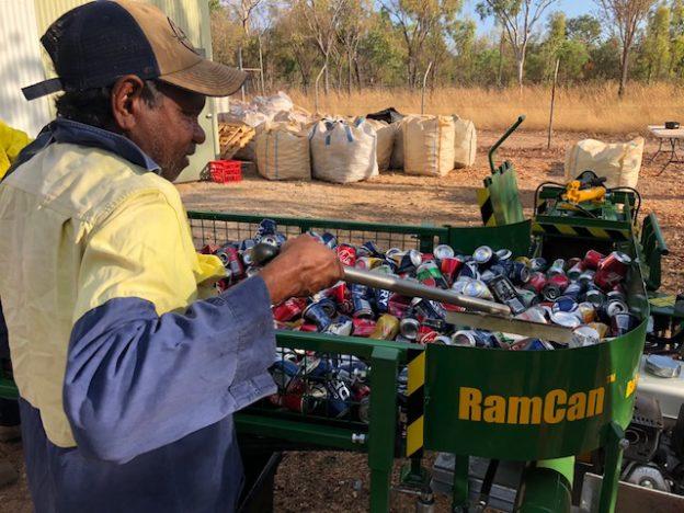 Council staff member using can crushing machine