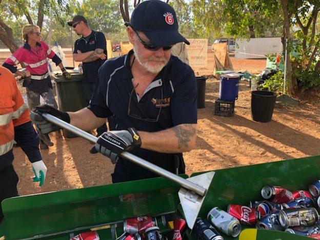 Council staff member using a can crushing machine