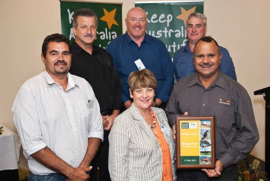 Five men and one woman standing in a group with an award smiling at camera