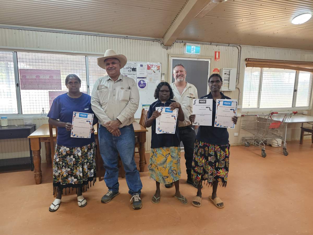 Three aged care staff holding certificates with the Mayor and CEO