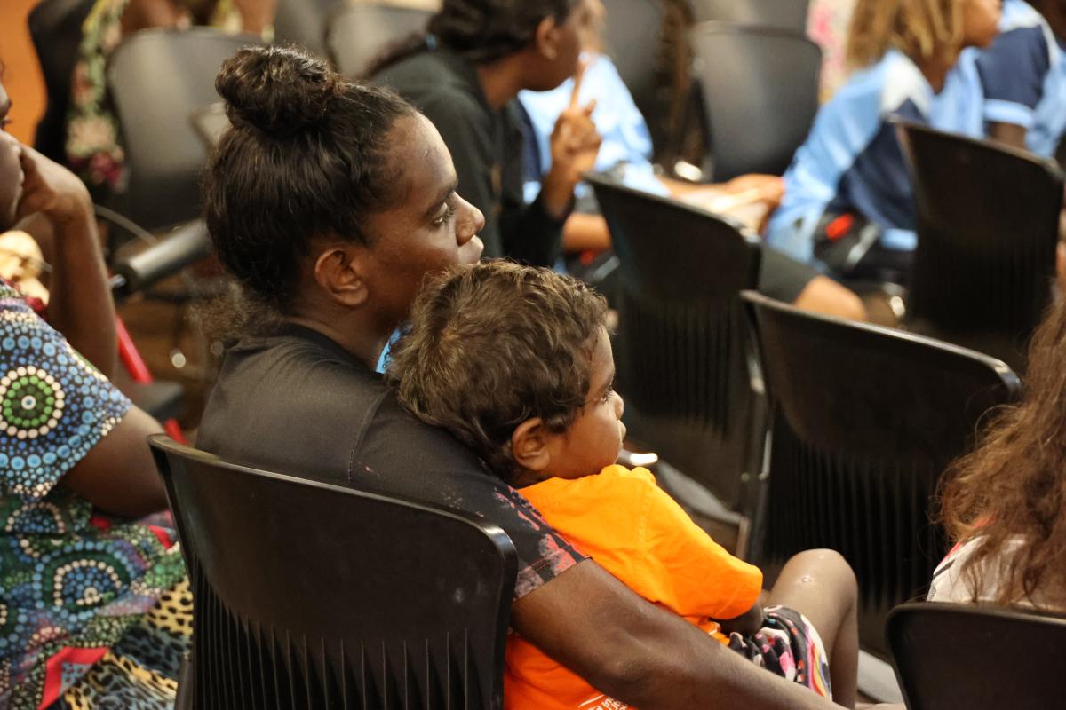 A women and her child sitting on a black chair in an audience