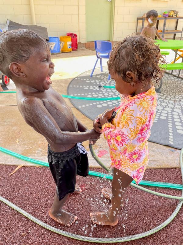 Two young kids playing with hose