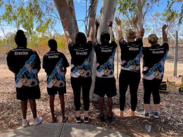 Childcare staff posing with backs to camera with new shirts