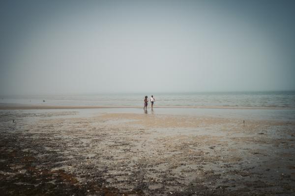 Two people standing on the beach on a foggy morning