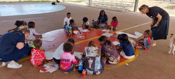 Children sitting on basketball court drawing pictures