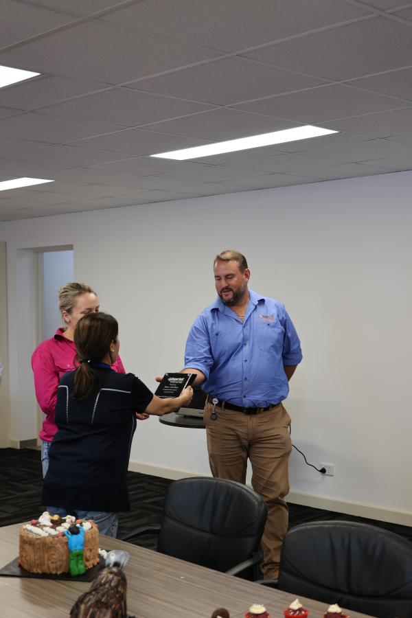 A women handing a plaque to Marc who is wearing a blue shirt