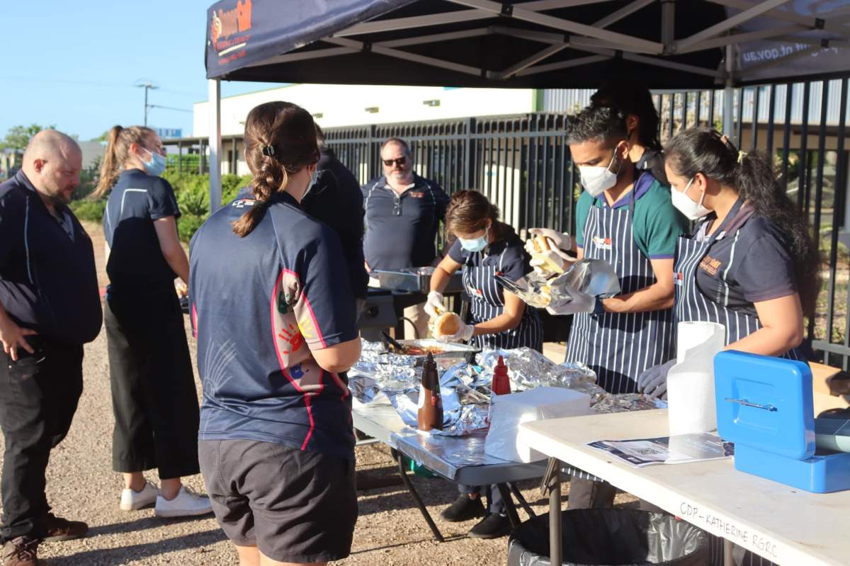 People serving bacon and eggs under marquee