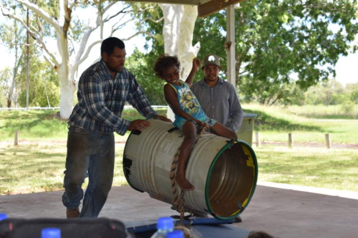Young child on top of an old drum pretending it is a bull