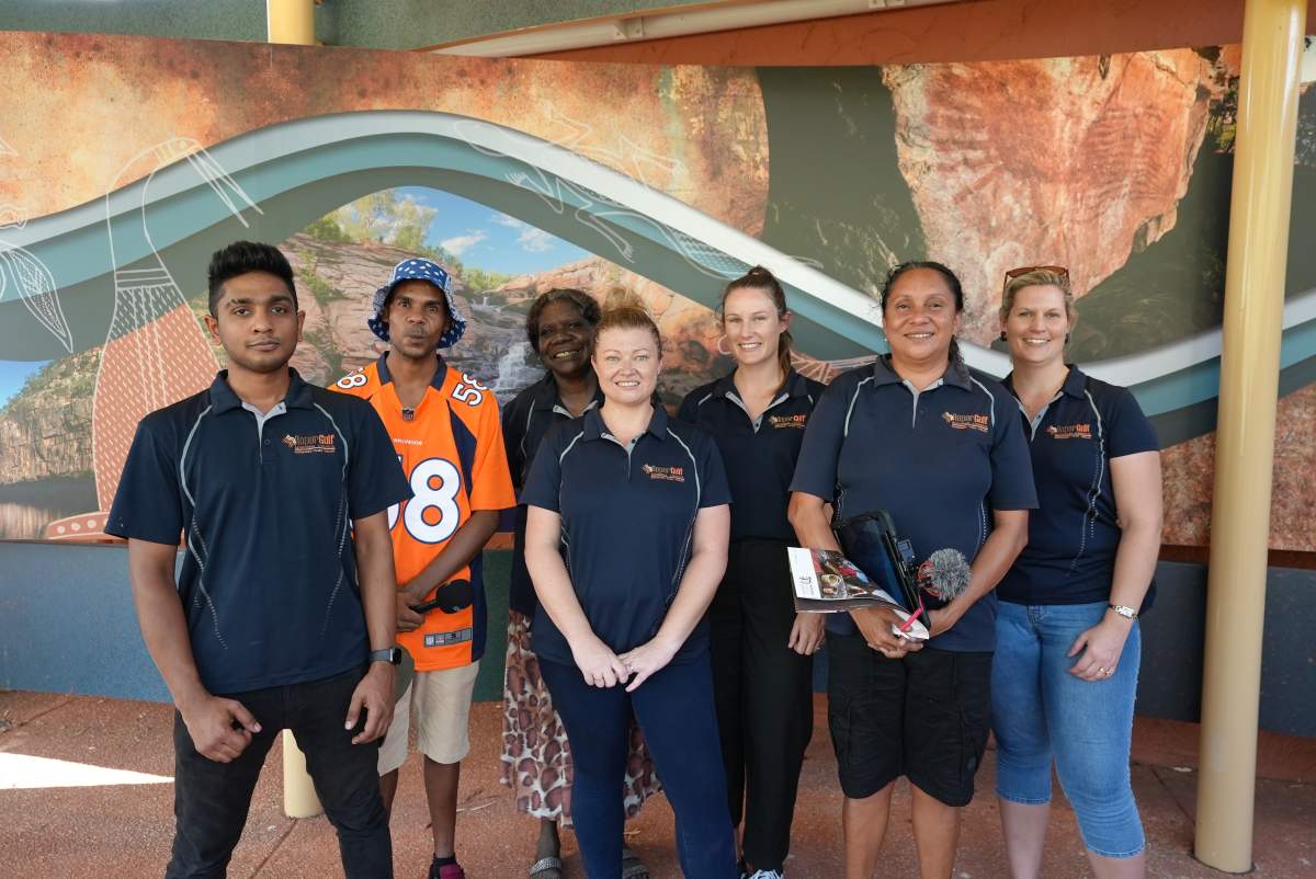 Seven people standing in a group smiling at camera