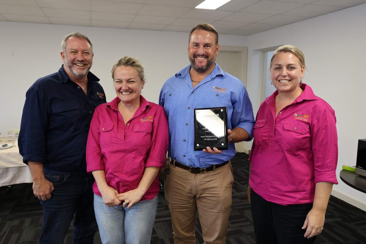 Four people smiling for camera in a rooms with white walls